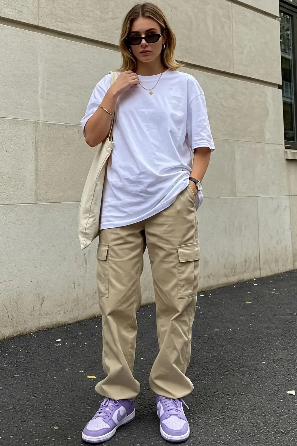 Model showcasing a neutral outfit with a white tee and beige cargo pants, highlighted by eye-catching lavender Nike Dunk Low sneakers.