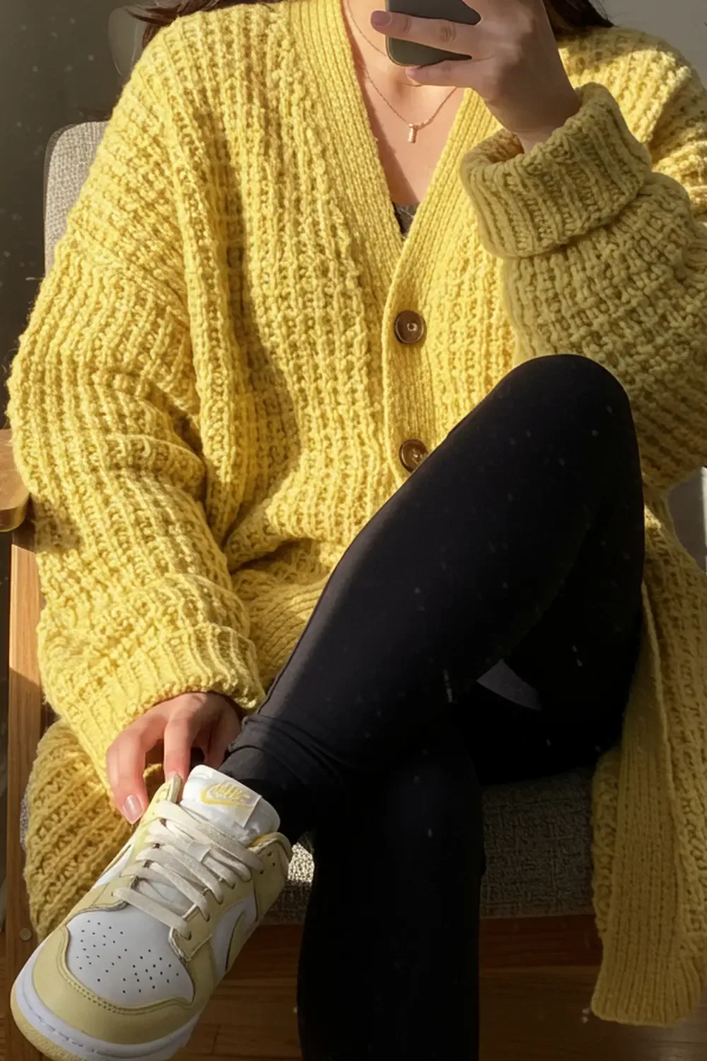 Person in a cozy work-from-home outfit: oversized pastel yellow cardigan, leggings, and matching Nike Dunk Lows.