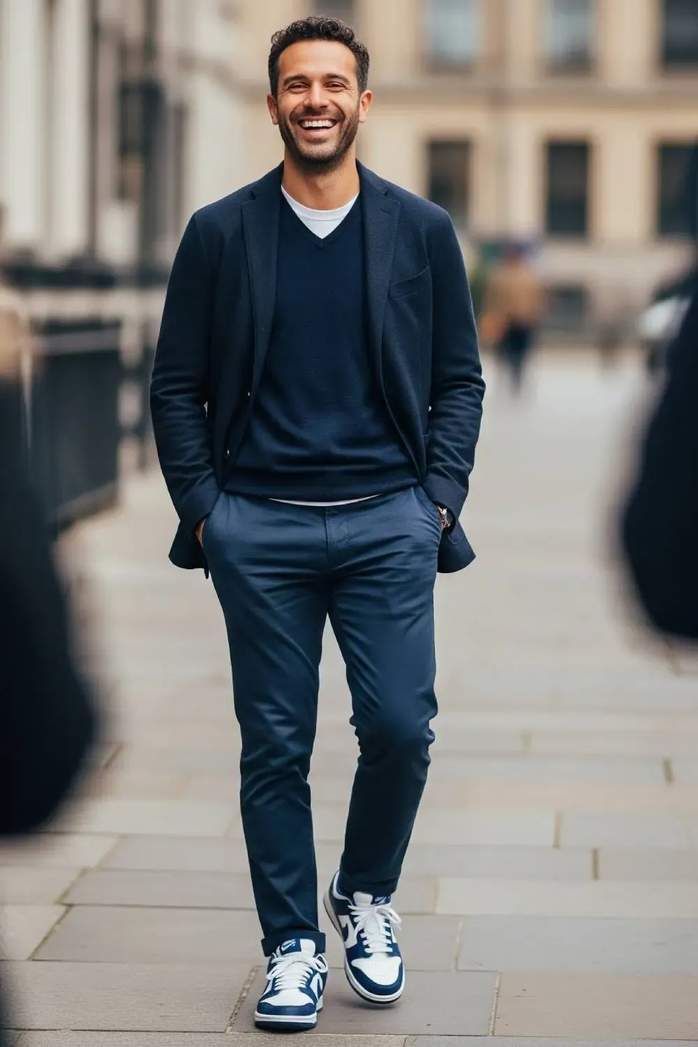 Man wearing a monochromatic navy outfit—chinos, sweater, and navy-accented Nike Dunk Lows—looking stylish for work.