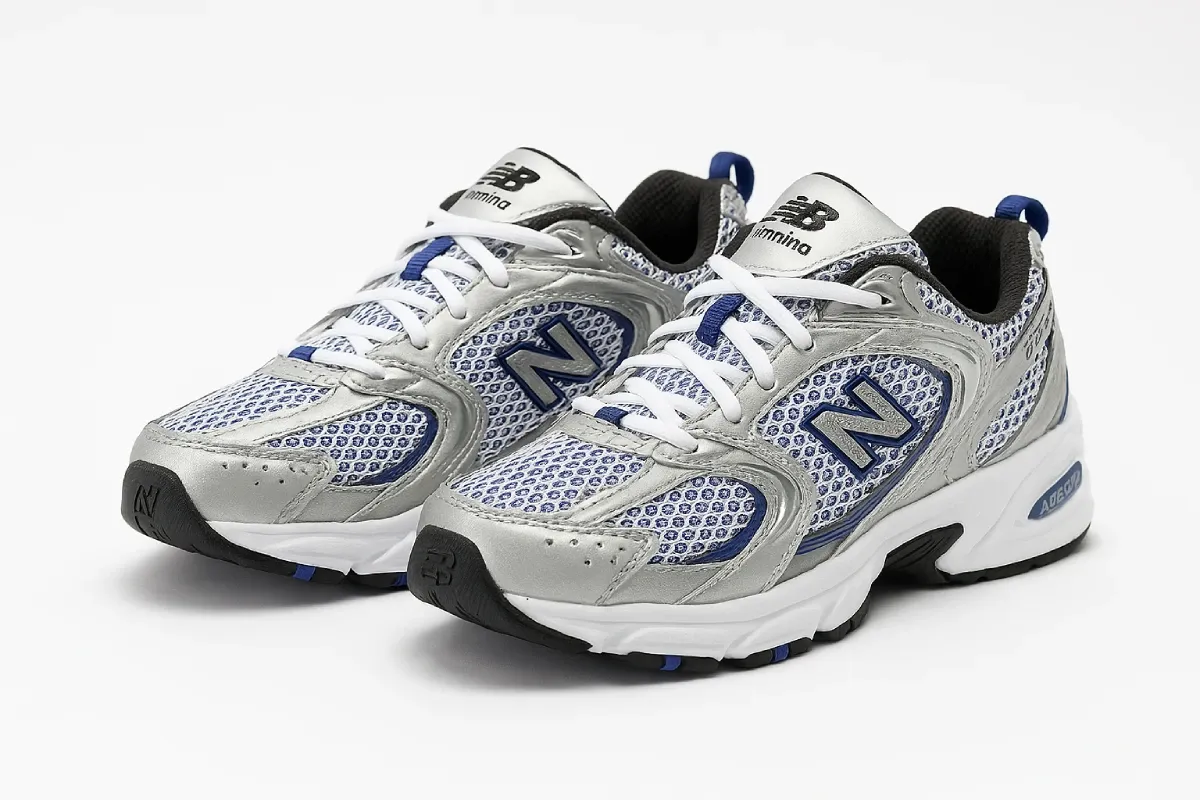 New Balance 530 running shoes with white/blue mesh upper, silver metallic overlays, ABZORB cushioning technology, breathable design, and black/blue outsole details - combining retro styling with performance features.